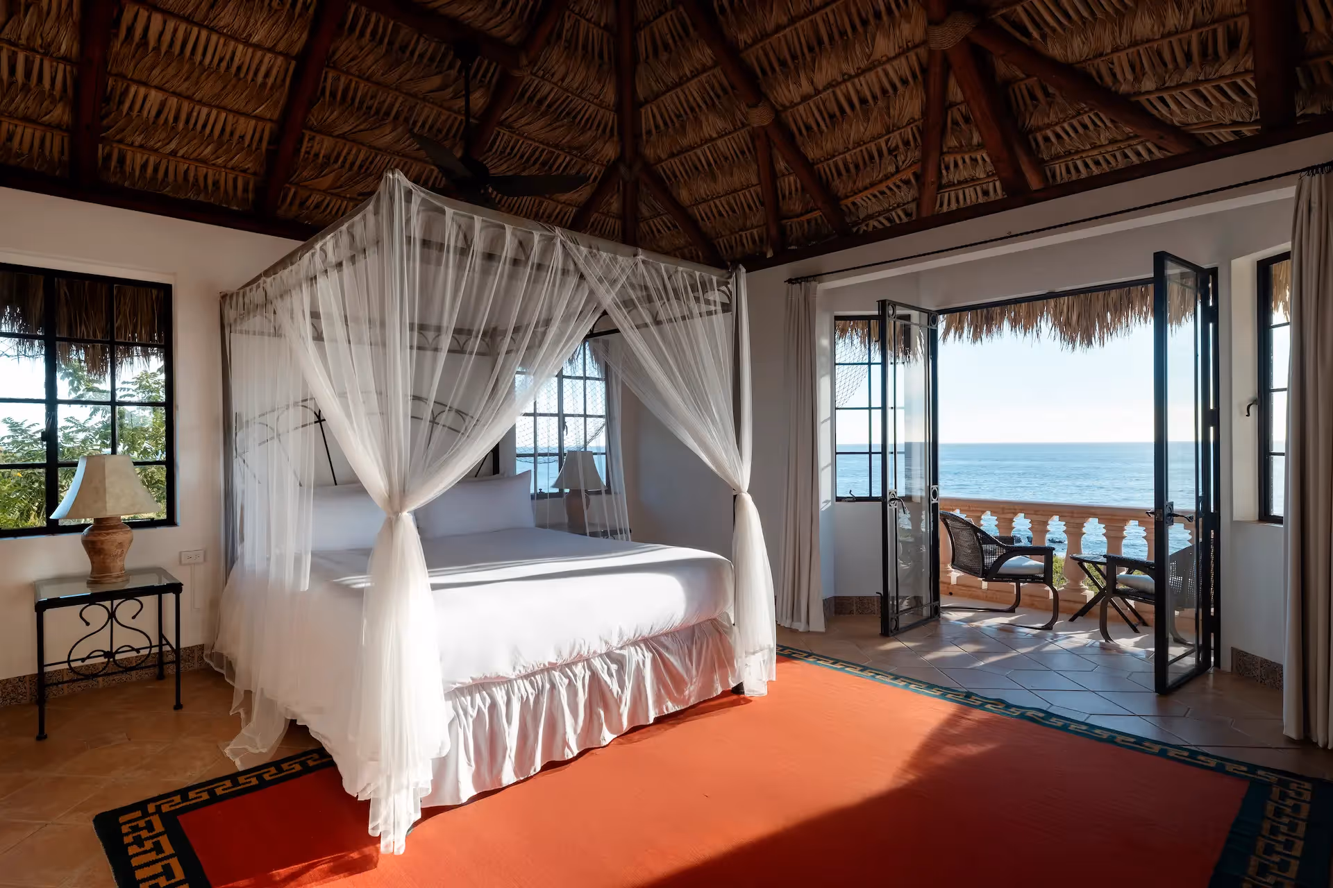 Luxury suite featuring a canopy bed and traditional palapa thatched roof at La Valise Los Cabos hotel.