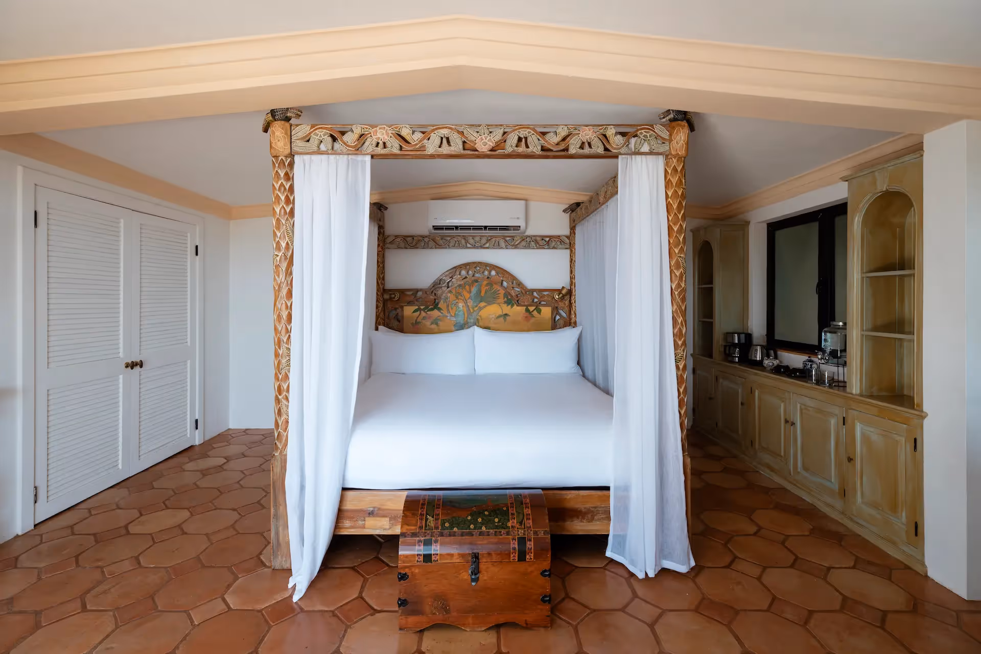 Luxurious suite featuring a canopy bed and terracotta floors at La Valise Los Cabos hotel.