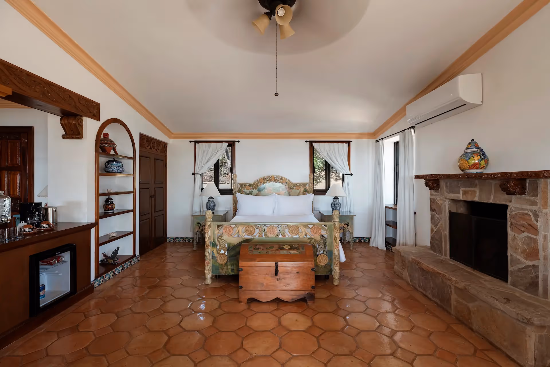 Amplio dormitorio con chimenea de piedra y suelo de baldosas de terracota en el hotel La Valise Los Cabos.