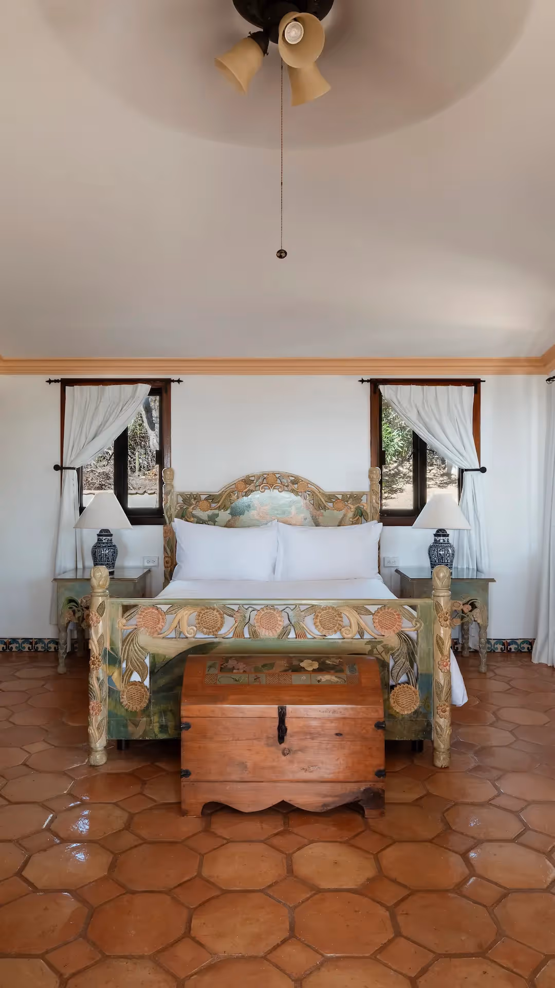 Amplio dormitorio con chimenea de piedra y suelo de baldosas de terracota en el hotel La Valise Los Cabos.