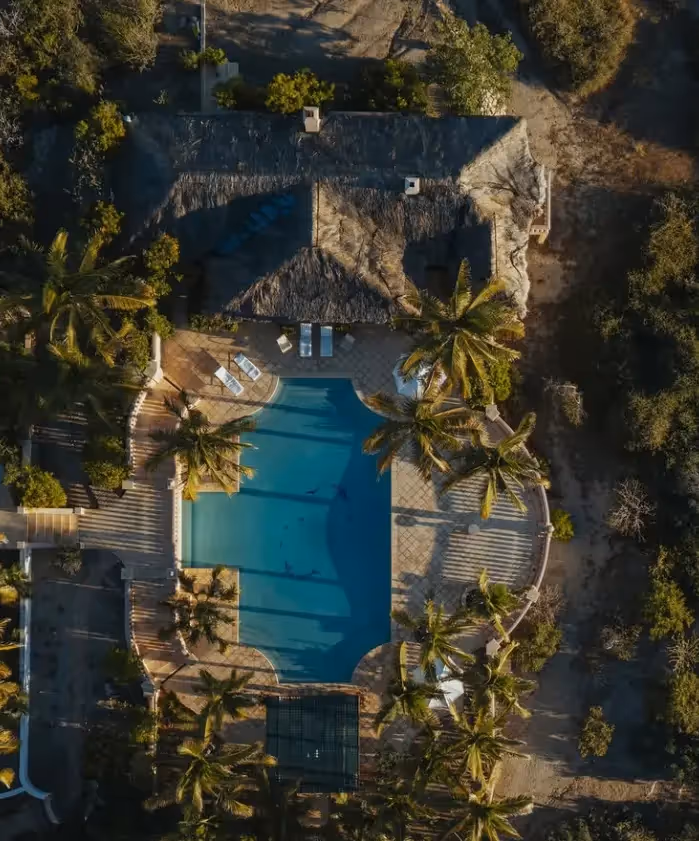 Suite de lujo en el hotel La Valise Los Cabos en México, con un diseño interior boho-chic con vigas de madera en el techo, sillas hechas a mano e iluminación ambiental cálida.