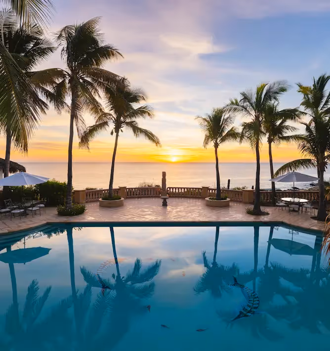 Espectacular puesta de sol en el océano reflejada en la piscina infinita del hotel La Valise Los Cabos.