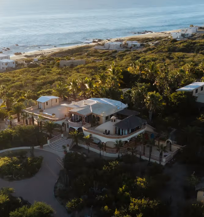 Vista panorámica aérea del hotel La Valise Los Cabos, ubicado en una exuberante vegetación a lo largo de la playa.