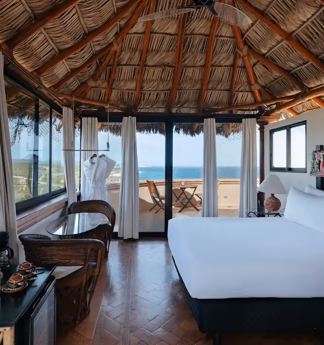 Suite de lujo con techo de palapa tradicional y vistas panorámicas al mar en el hotel La Valise Los Cabos.