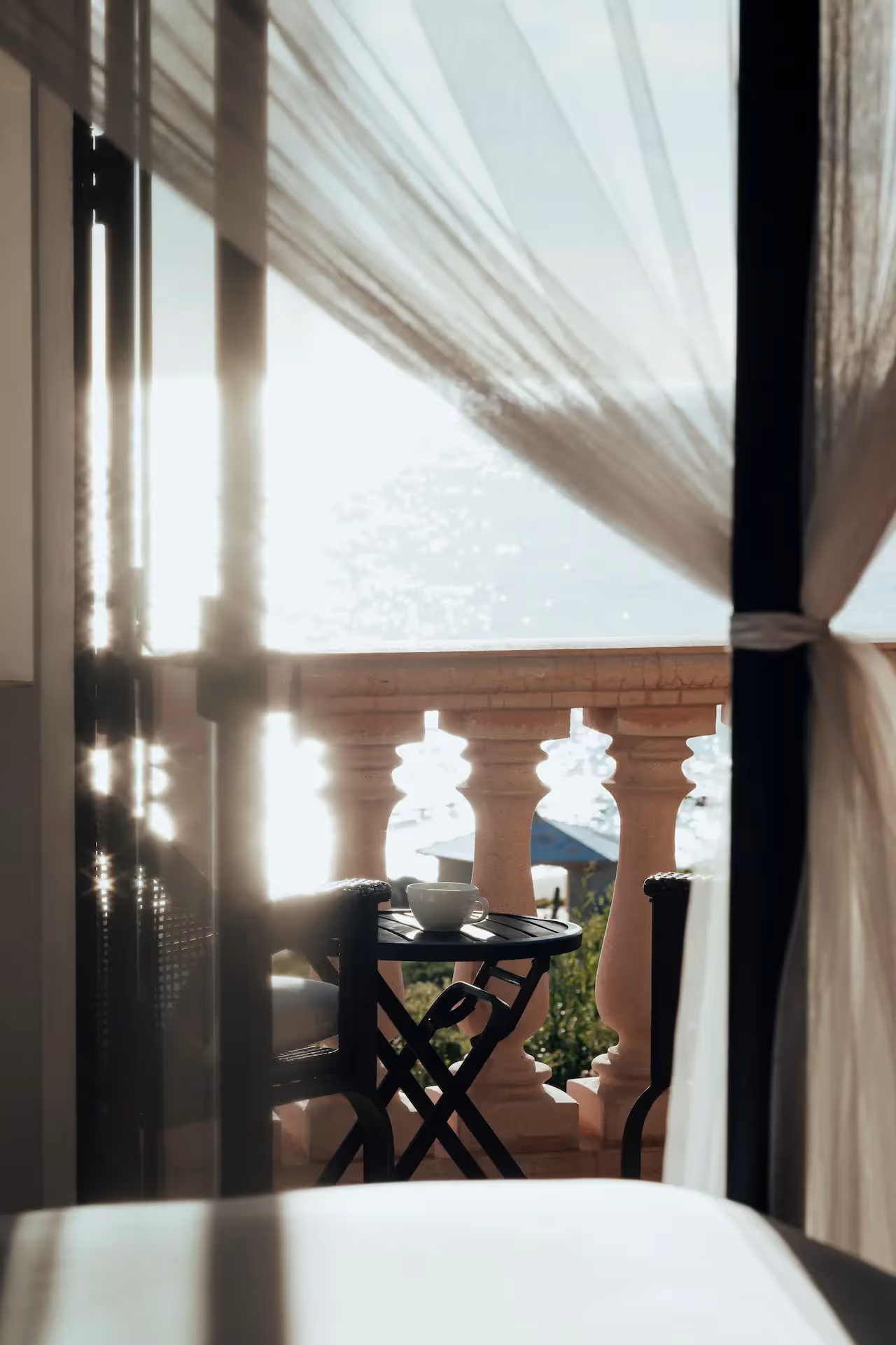 El balcón privado del hotel La Valise Los Cabos ofrece vistas al mar a través de cortinas transparentes, perfecto para un desayuno en la terraza al aire libre.