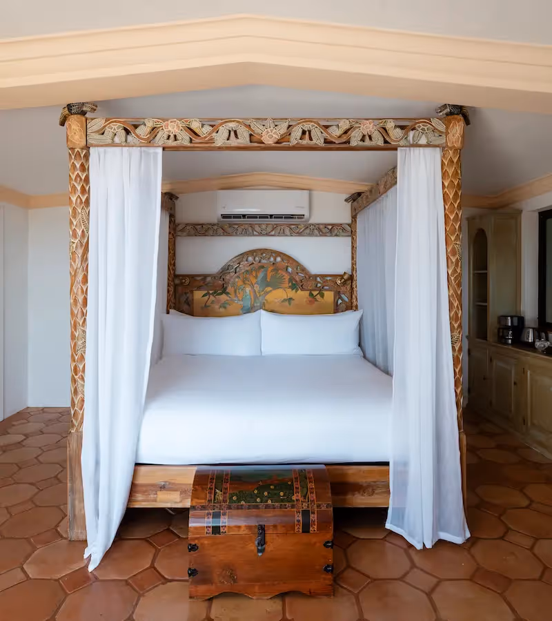 Amplio dormitorio con chimenea de piedra y suelo de baldosas de terracota en el hotel La Valise Los Cabos.