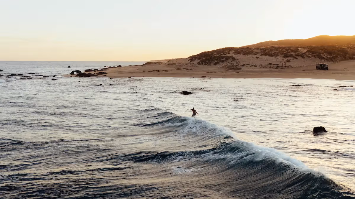 Vista panorámica de las olas del océano y la playa salvaje en el restaurante del hotel La Valise Los Cabos durante la puesta de sol.
