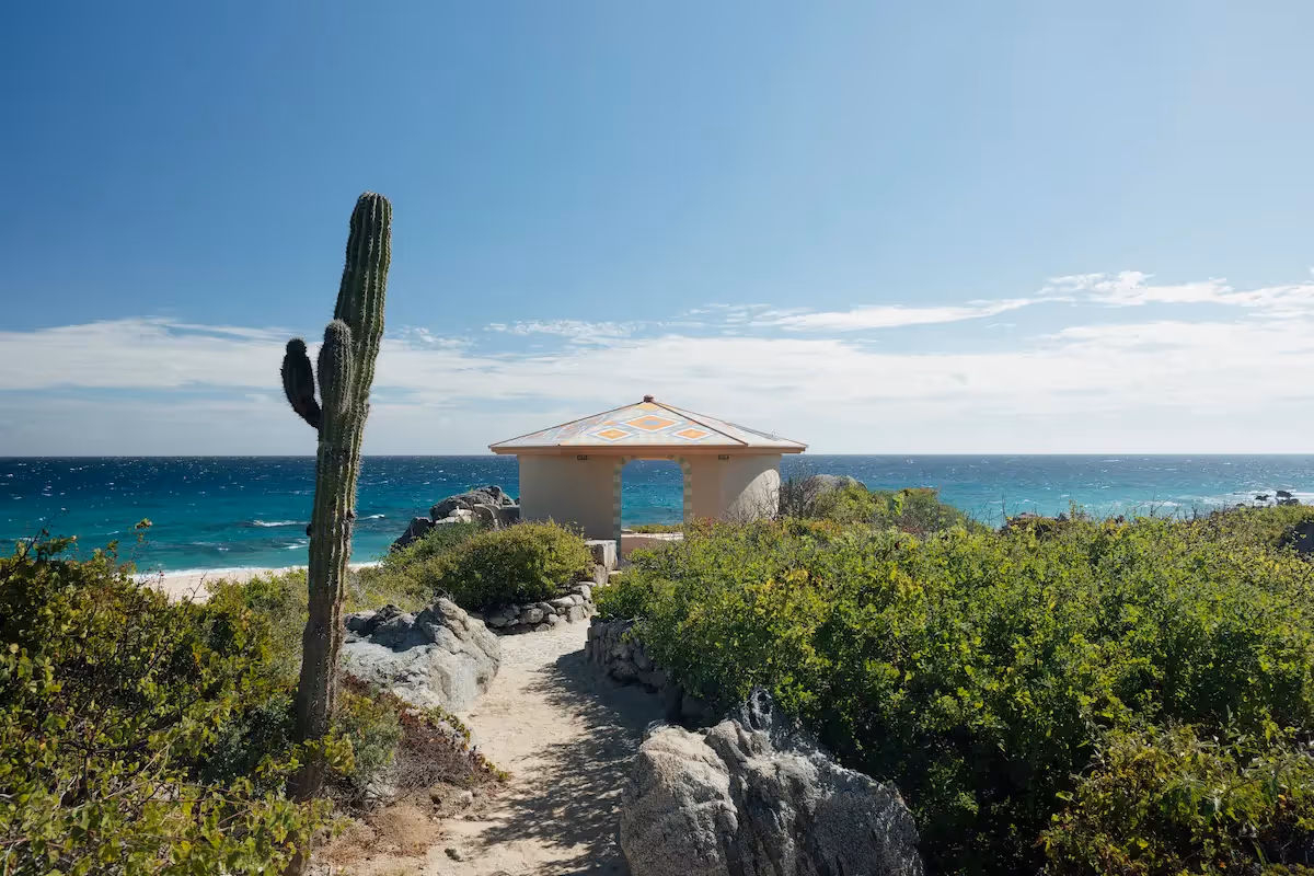 Ocean view from the coastal path at La Valise Los Cabos hotel restaurant, featuring a cactus and a seaside pavilion.
