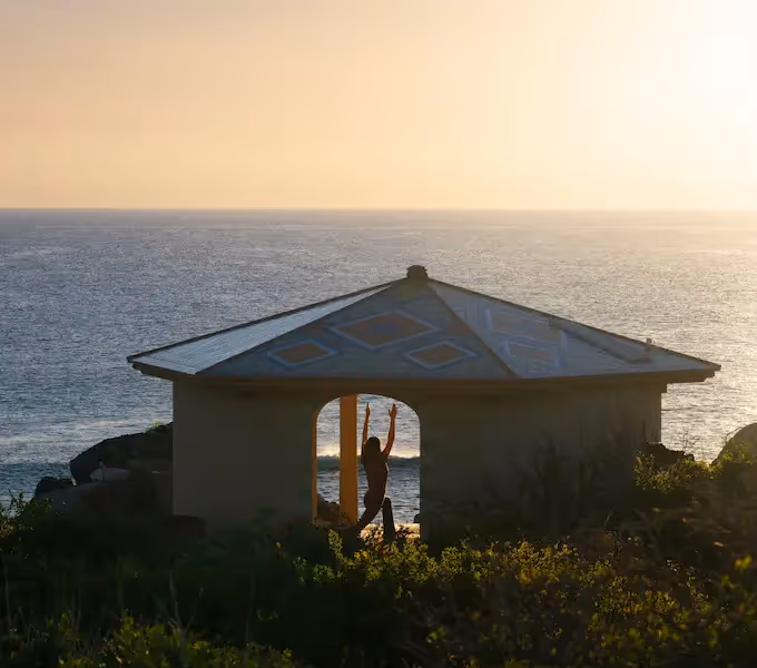 Silueta de una persona practicando yoga en un pabellón abierto frente al mar al atardecer en el hotel La Valise Los Cabos.