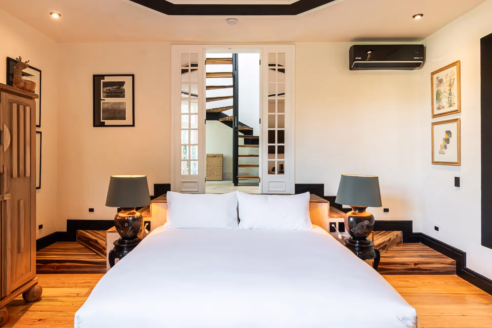 Bright guest room featuring a designer staircase in the background at La Valise Mexico City Hotel.