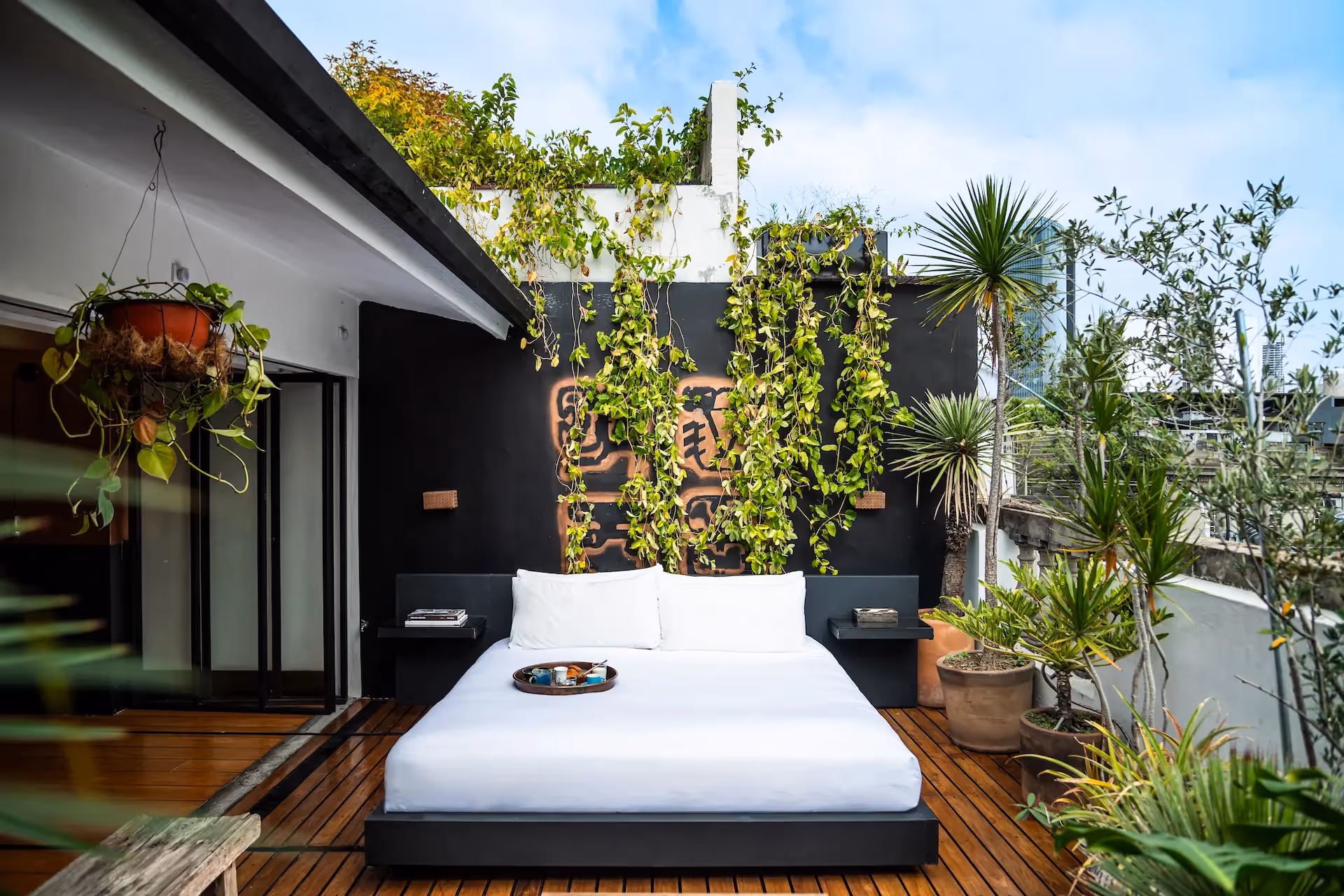Outdoor bed on a private terrace with a lush green wall at La Valise Mexico City Hotel.