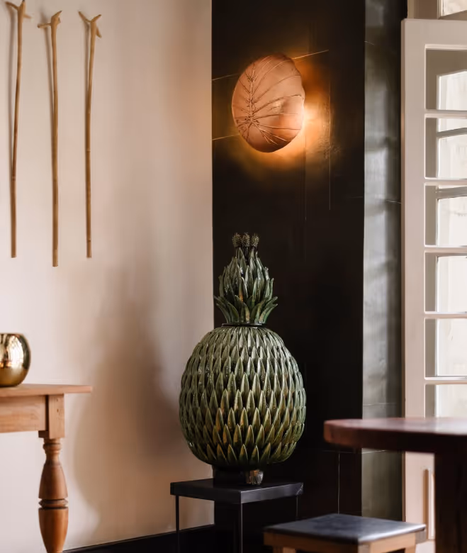 Elegant interior decor at La Valise Mexico City hotel, featuring a handcrafted green pineapple sculpture and a designer wall sconce.