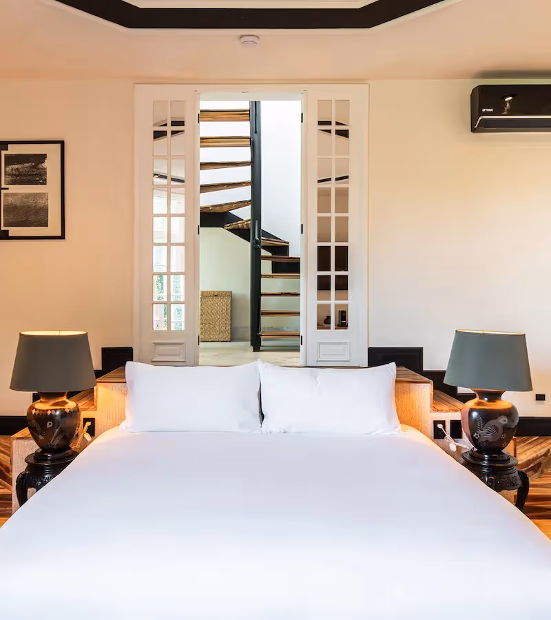 Bright guest room featuring a designer staircase in the background at La Valise Mexico City Hotel.