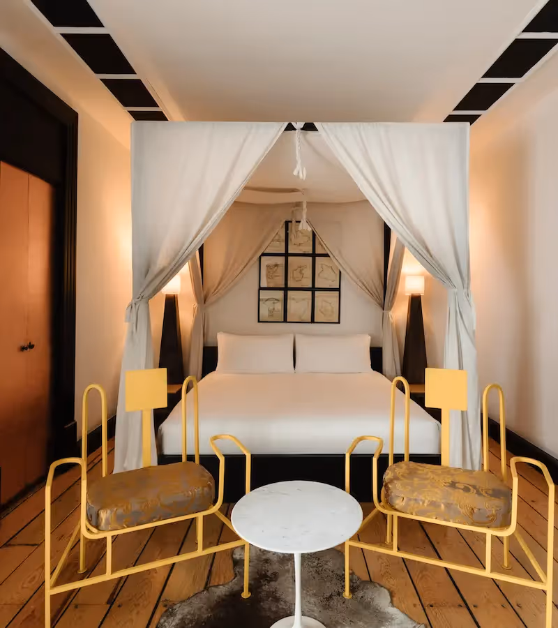Elegant canopy bed with white drapes in a luxury suite at La Valise Mexico City Hotel.