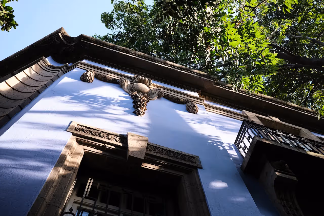Fachada del hotel La Valise de la Ciudad de México con detalles arquitectónicos clásicos bajo los árboles en Roma.