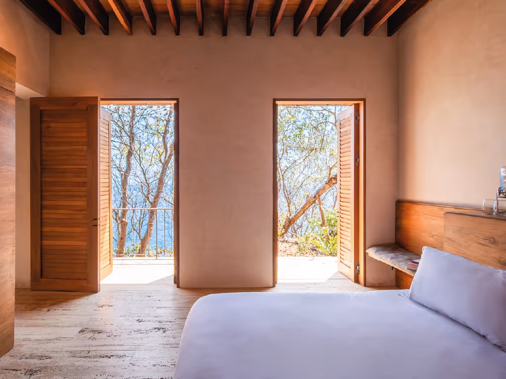 Serene bedroom with double doors opening to the ocean at La Valise Mazunte Hotel.