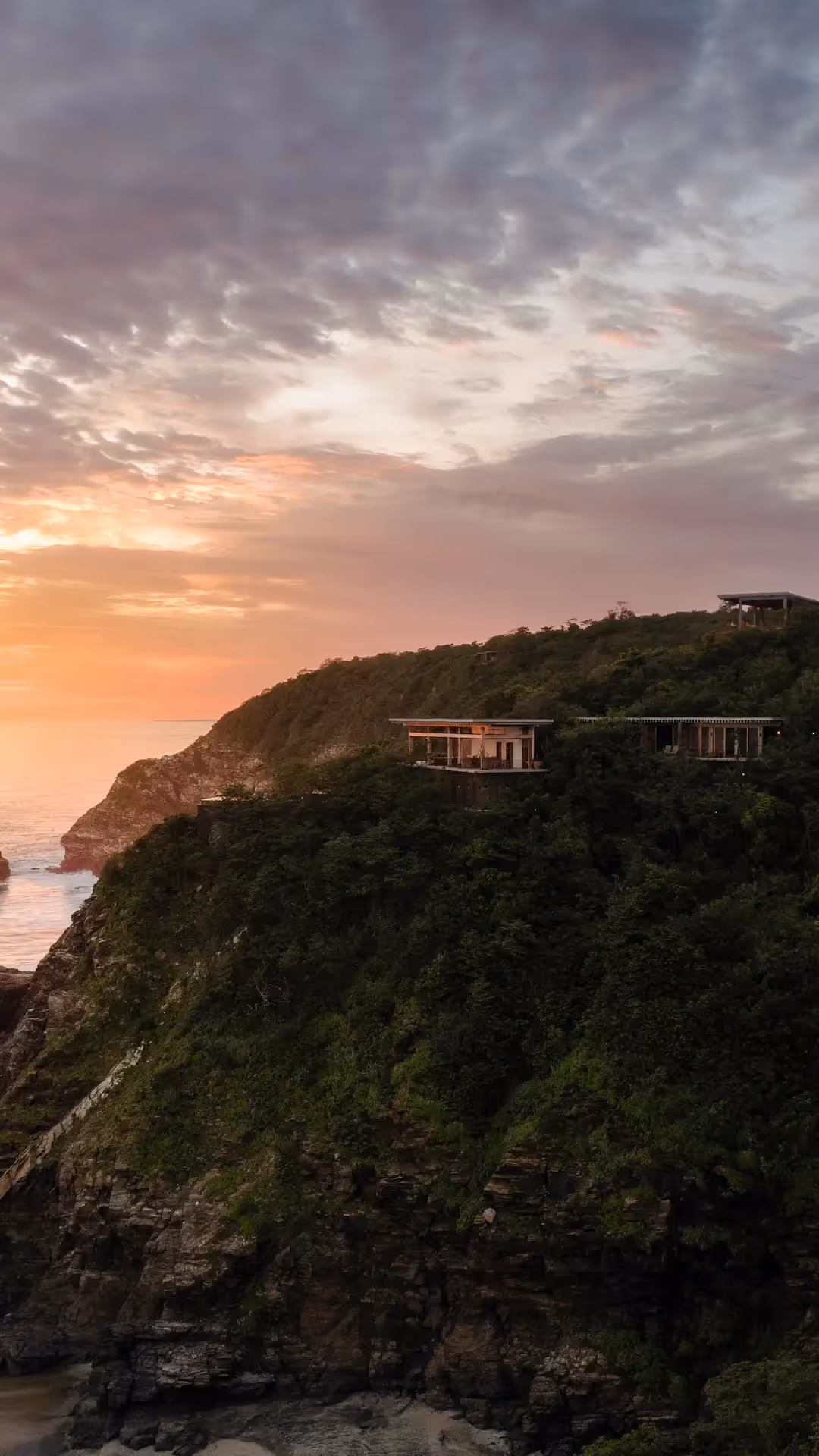 Aerial view of the white sand beach and tropical architecture of La Valise Mazunte Hotel nestled in the jungle.