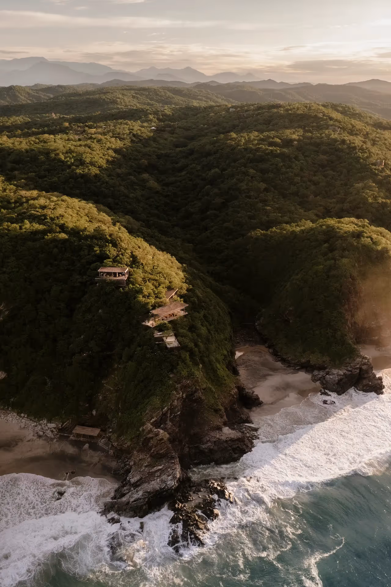 Aerial view of the lush cliffs and pristine beach surrounding the restaurant at La Valise Mazunte Hotel in Mexico.