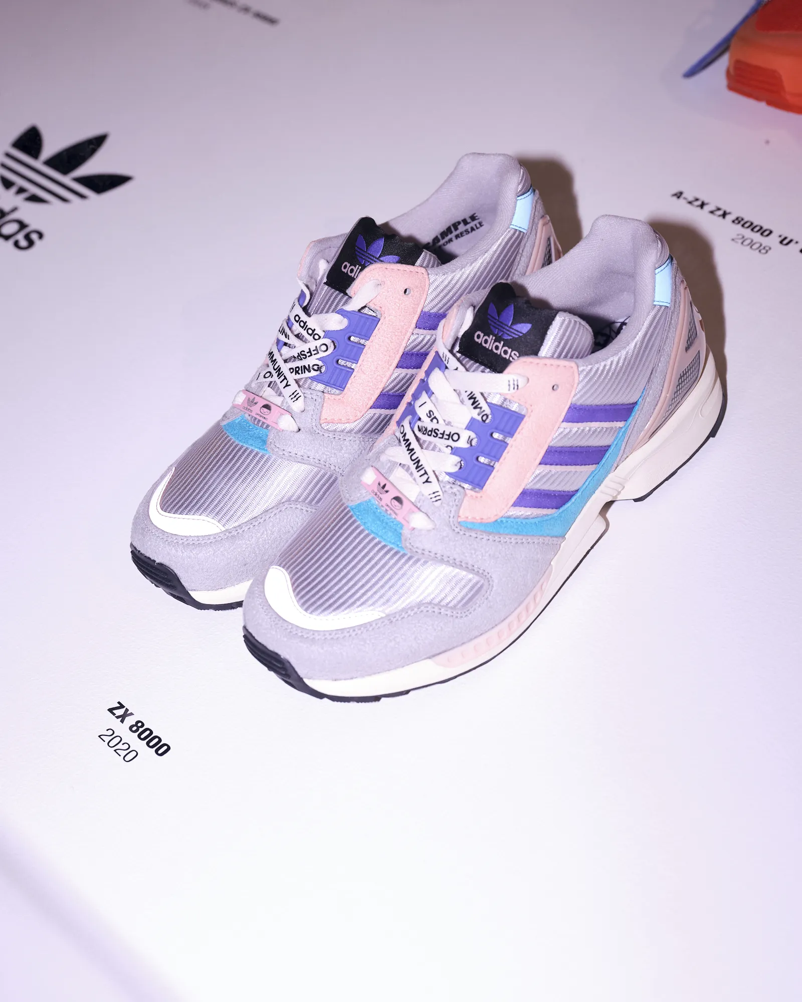Pair of Adidas ZX 8000 sneakers in pastel pink, purple, grey, and blue on white surface with model and year labels.