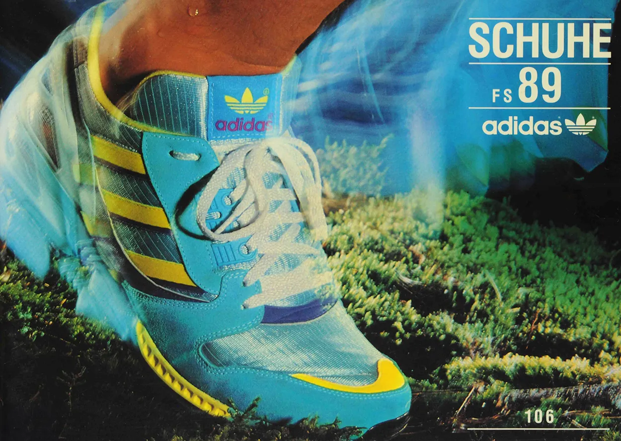 Close-up of a blue Adidas sneaker with yellow stripes and white laces on grass, with text 'SCHUHE FS 89 adidas'.