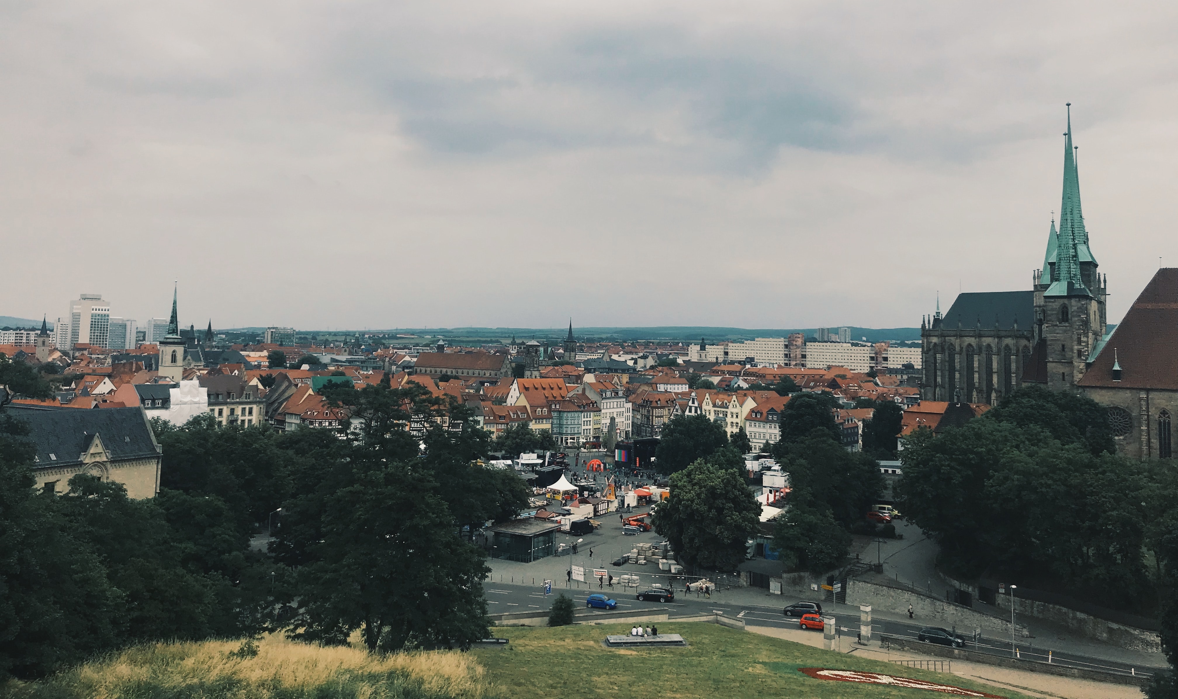 Vier lachende junge Erwachsene, zwei halten eine bunte Schüssel mit Salat und Falafel vor einem orangefarbenen Hintergrund.