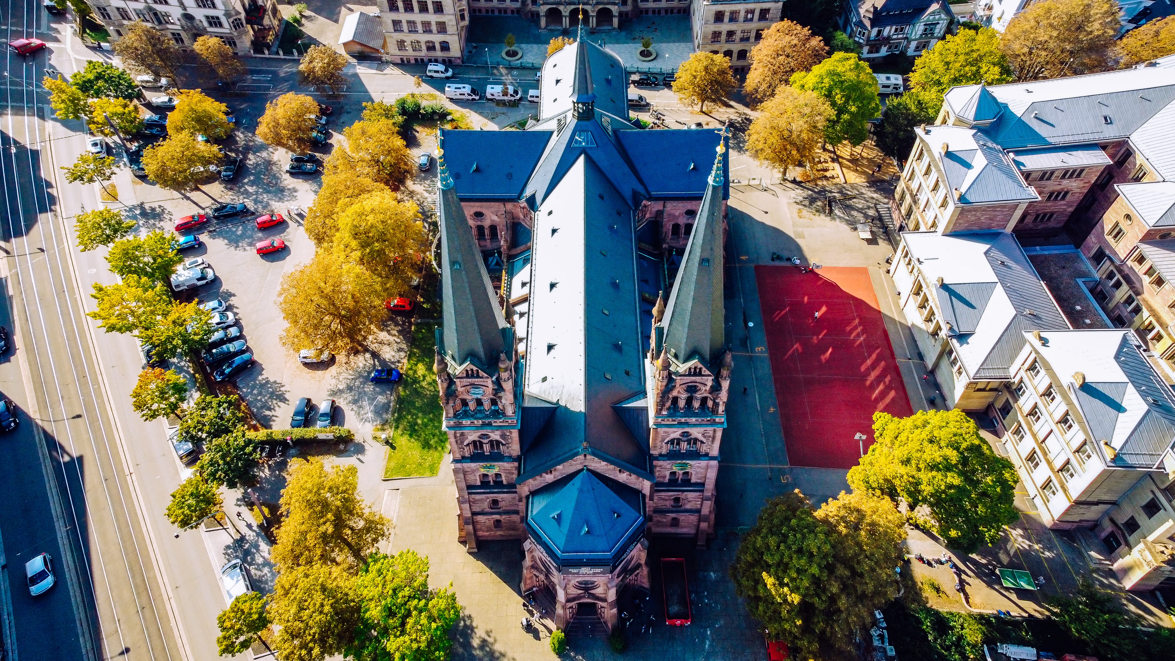 Vier lachende junge Erwachsene, zwei halten eine bunte Schüssel mit Salat und Falafel vor einem orangefarbenen Hintergrund.