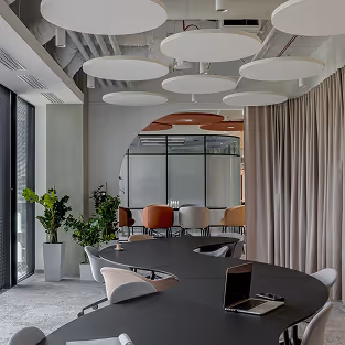 Modern meeting room with round acoustic baffle ceiling panels above a conference table.