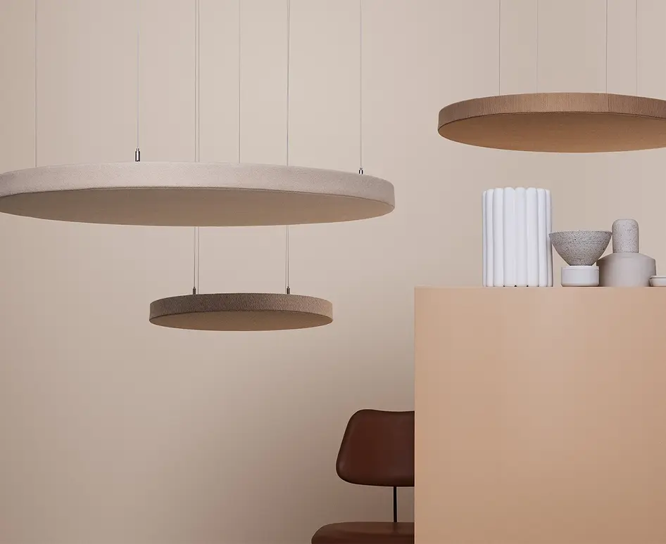 Round felt acoustic pendant ceiling panels suspended in a warm neutral interior with a leather chair.