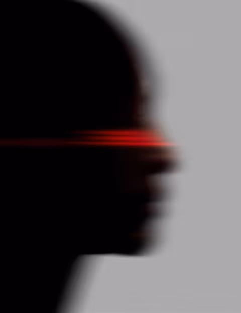 Blurred dark profile of a head with a red glowing band across the eyes on a grey background.