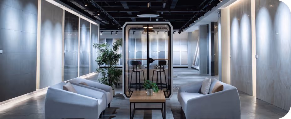 Acoustics showroom with backlit panel displays, glass meeting pod and grey lounge seating.