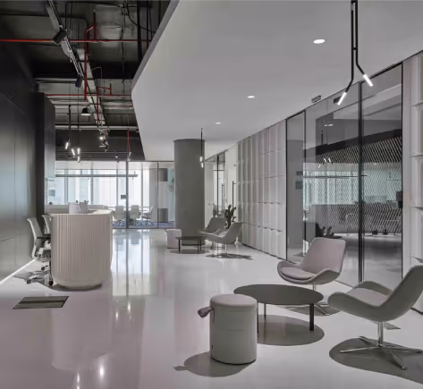 Minimal grey office breakout area with acoustic mesh partition walls and soft seating.