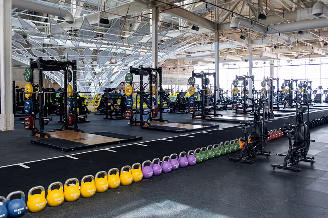 Large commercial gym fitted with acoustic ceiling treatment, rows of kettlebells and weight racks.