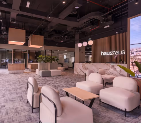 Haushaus office reception lounge with acoustic wall slats, upholstered chairs and marble counter.