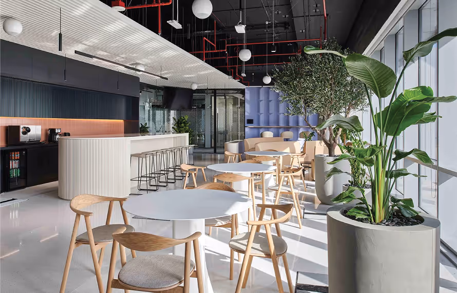Modern office cafe with fluted acoustic ceiling baffles, wooden chairs, and upholstered acoustic wall panels.