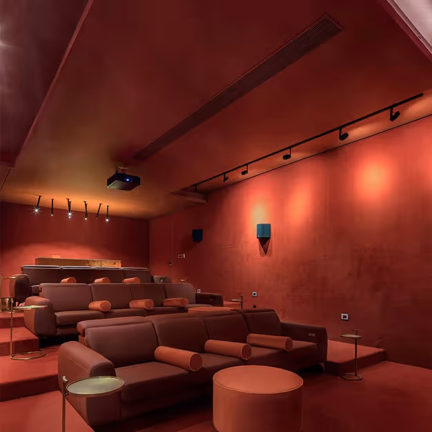 Sound-absorbing red velvet walls and ceiling in a luxury home cinema with tiered seating.