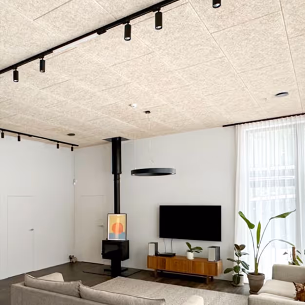 PET felt acoustic ceiling panels installed across a bright living room with a wood-burning stove.