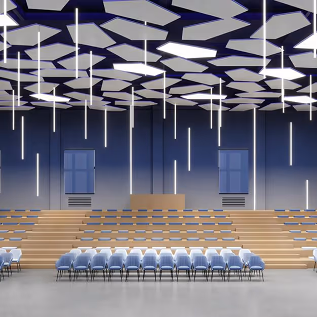 Hexagonal acoustic ceiling baffles suspended in a modern auditorium with tiered seating and pendant lighting.