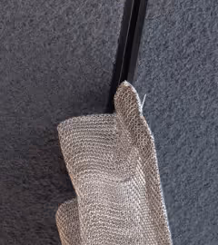 Folded metallic mesh acoustic element mounted against a textured wall.