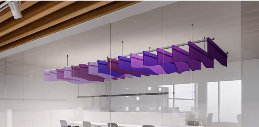 Multicolored purple suspended acoustic baffles hanging above a glass-walled meeting room.