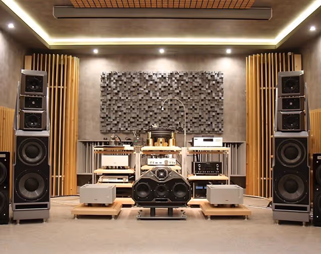 High-end audio listening room with a wood-block acoustic diffuser panel behind speakers.