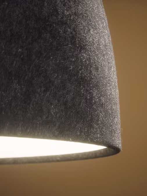 Close-up of a glowing grey felt acoustic pendant lamp.