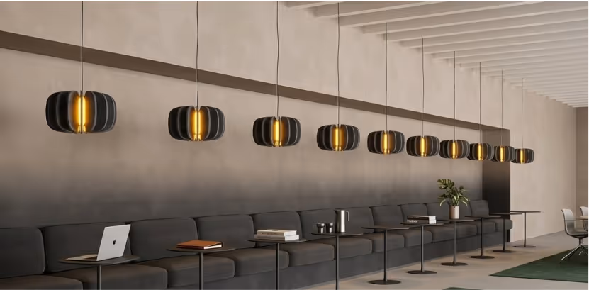 Row of scalloped black and gold felt acoustic pendant lights above an office lounge sofa.