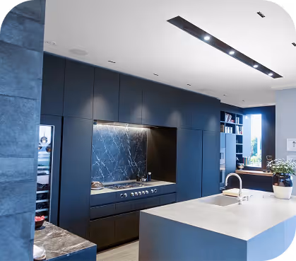 Modern deep-blue kitchen interior with marble backsplash and a large stone island.