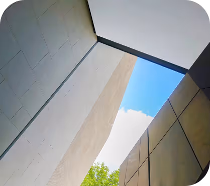 Upward view of a building's tiled facade panels meeting an open blue sky.
