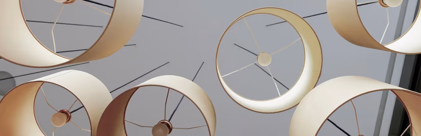 Cluster of drum-shade acoustic pendant lamps viewed from below against a grey ceiling.
