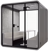 Green compact acoustic work pod with stool and shelf for focused office tasks.
