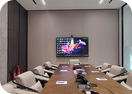 Conference room with wood-slat ceiling, long table and a large wall-mounted display screen.