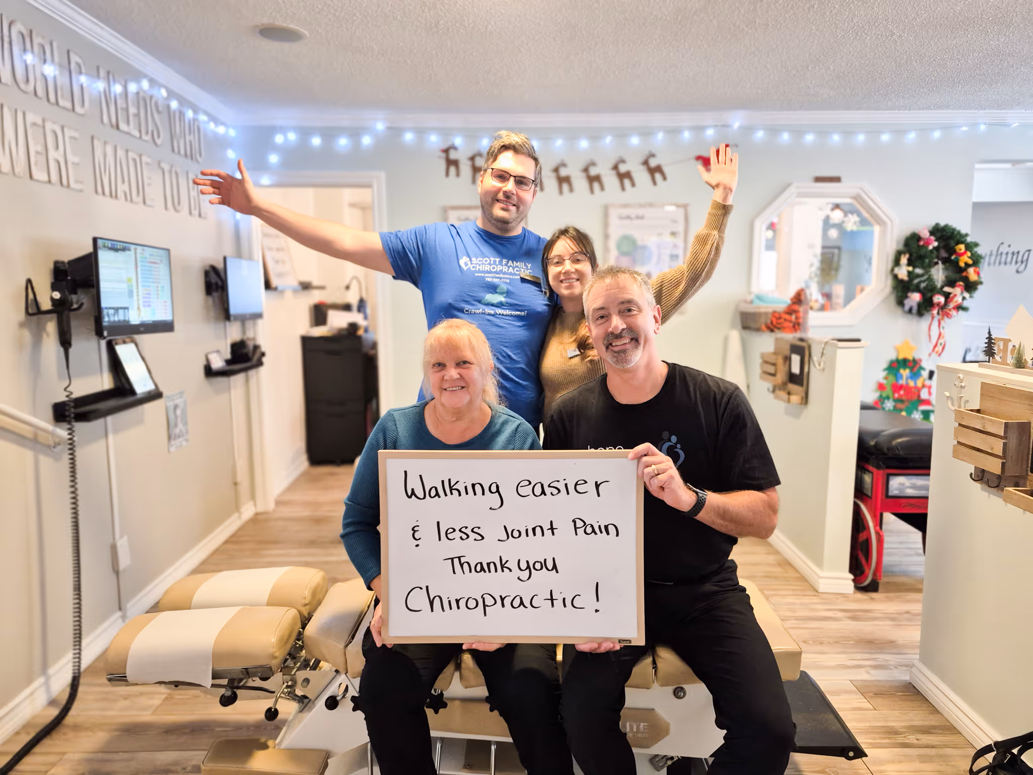 Smiling man wearing a black t-shirt with the word 'Hope' in white script, standing in front of a light-colored brick wall with a green plant on the side.