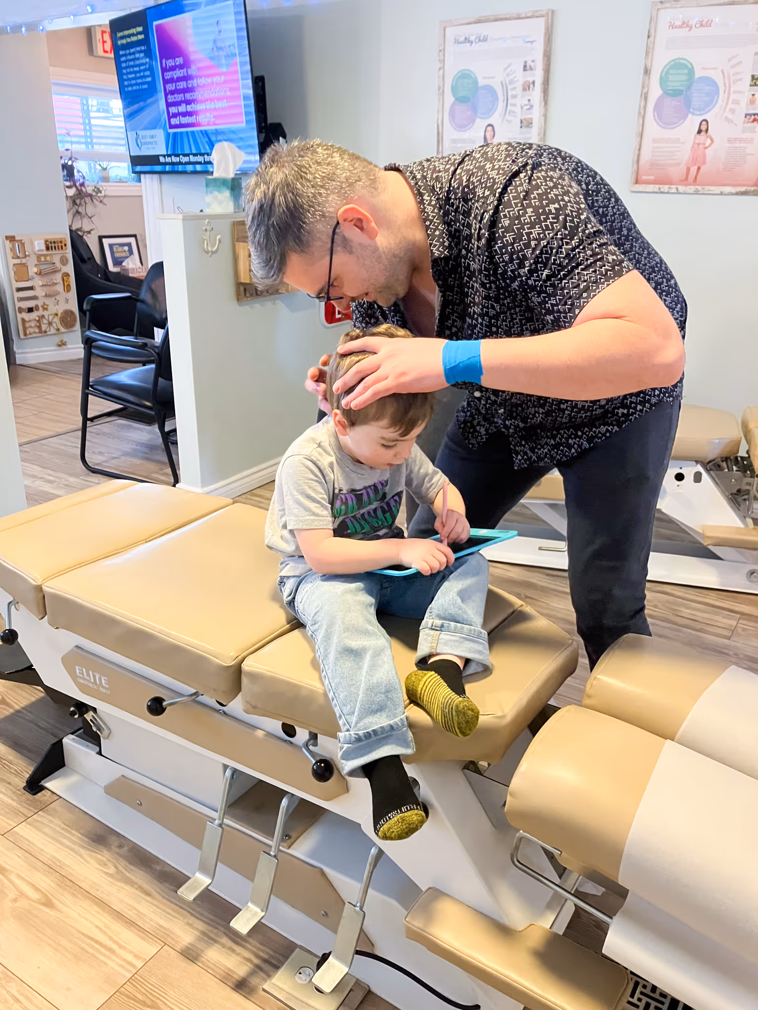 A man standing behind a woman with braided hair, assessing her posture using a grid chart labeled PostureZone.