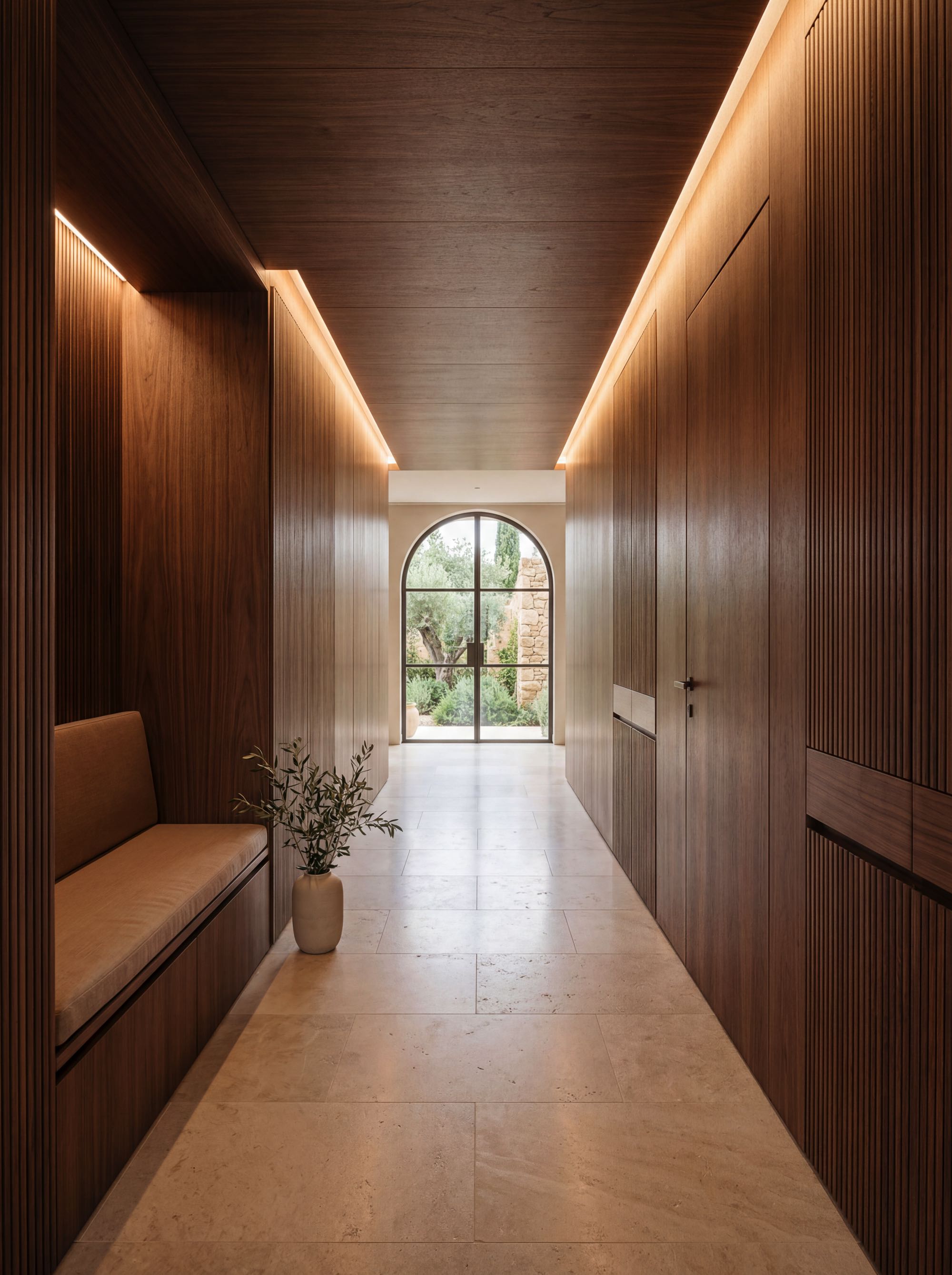 Minimal luxury hallway with full-height walnut wall panels, hidden flush door, integrated storage and warm indirect lighting in a Mediterranean villa interior by AXON.